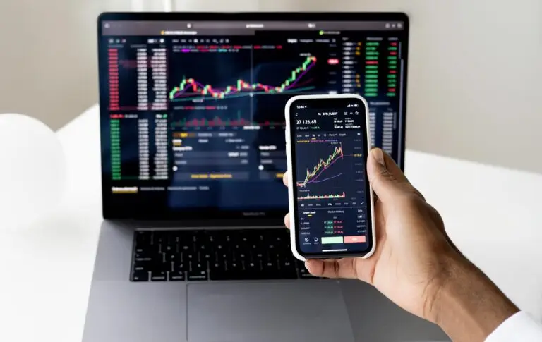 Elementor Page #585 Person checking stock market graphs on laptop and smartphone, focusing on financial data.